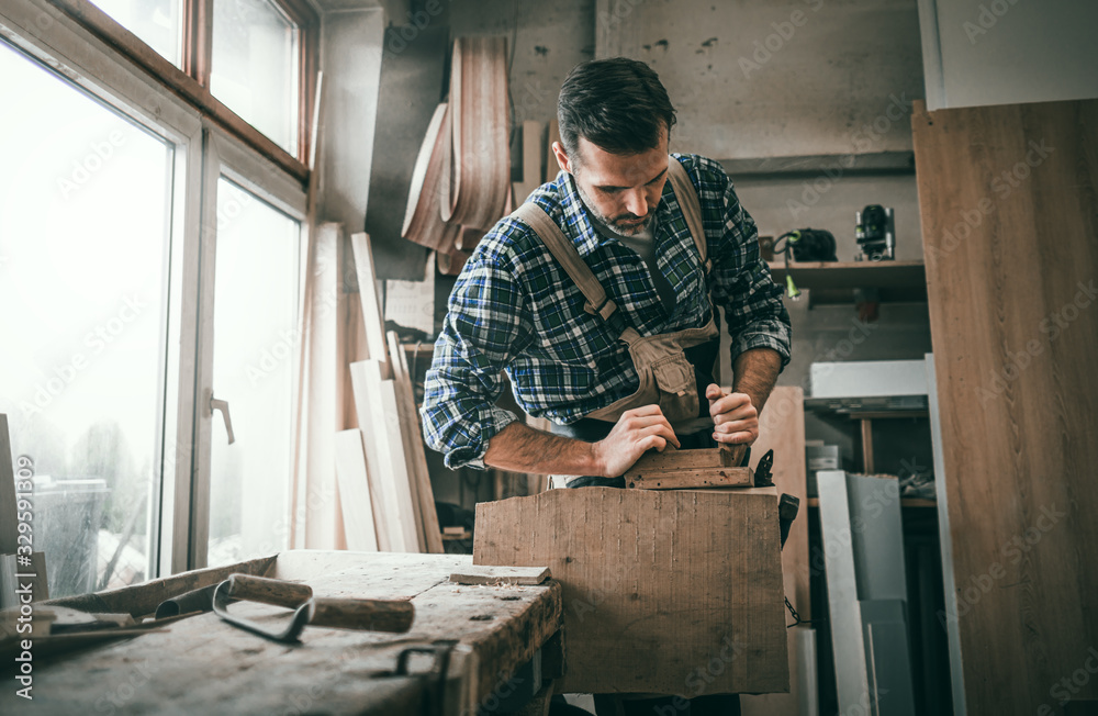 Carpenter using woodworking tools for craft work in carpentry workshop