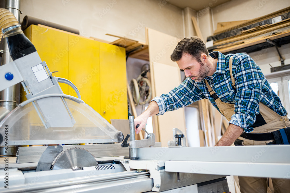 Carpenter preparing circular saw to work at carpentry workshop