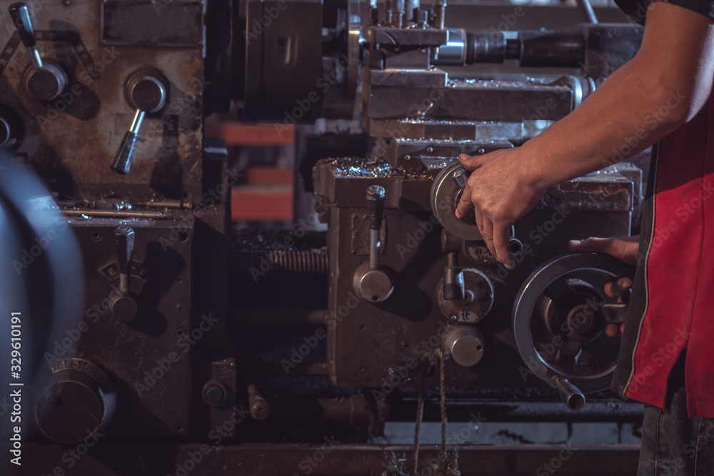 Close-up Worker handles metal at lathe operating lathe grinding machine in uniform with safety - met