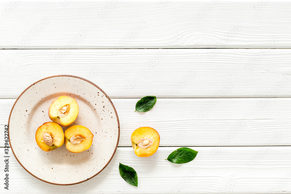 Healthy food. Ripe sliced peaches on plate on white wooden table top-down copy space