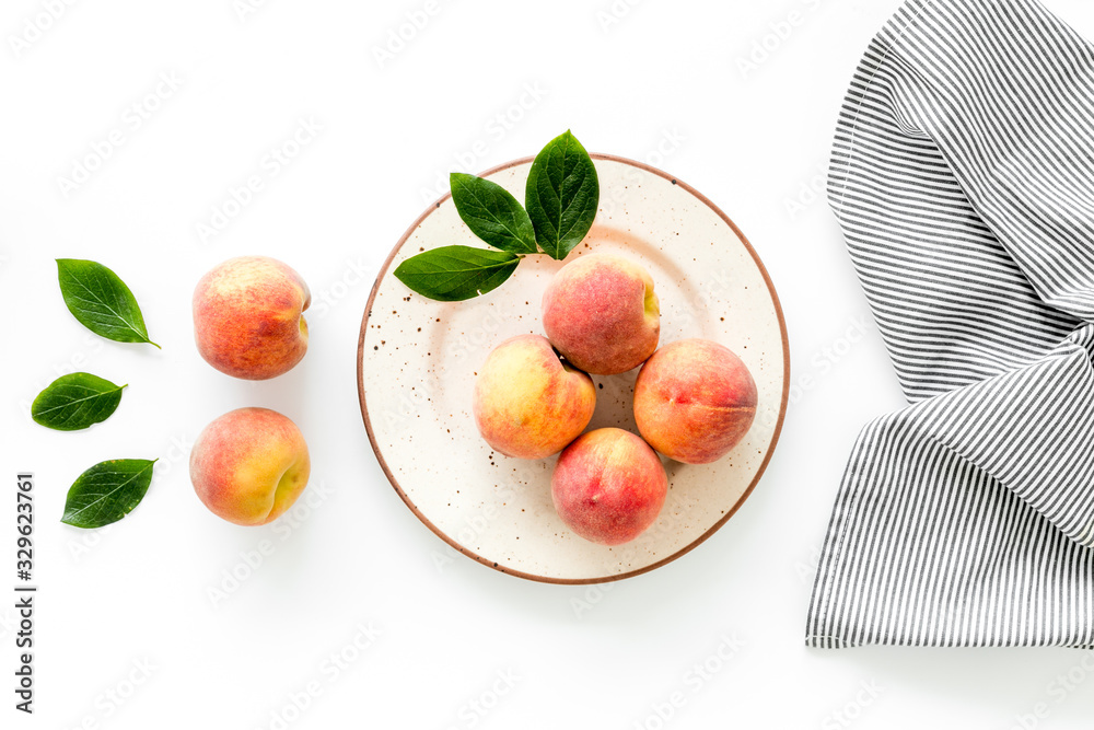 Summer lunch. Red peaches on white background with tablecloth and leaves top-down