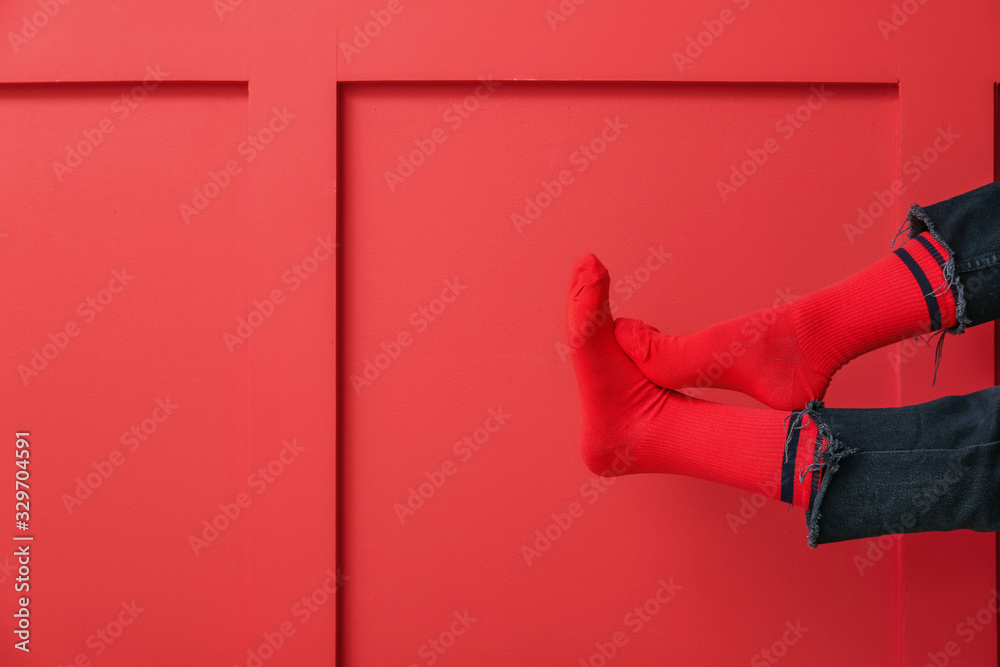 Legs of young woman in socks and jeans on color background