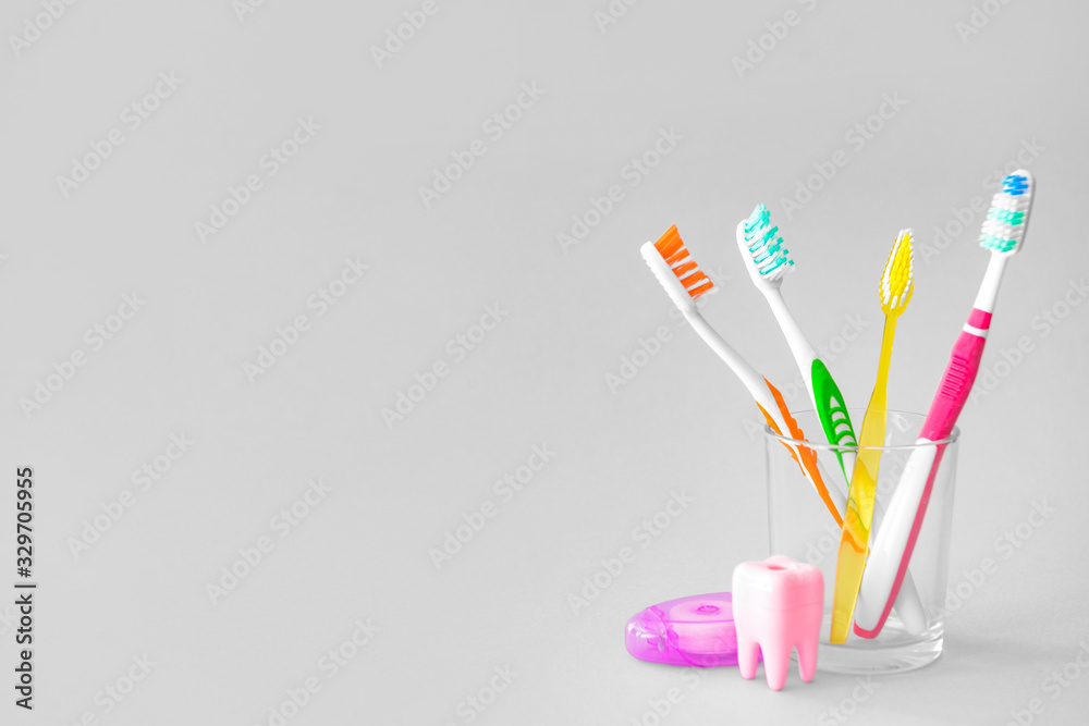 Glass with tooth brushes on light background