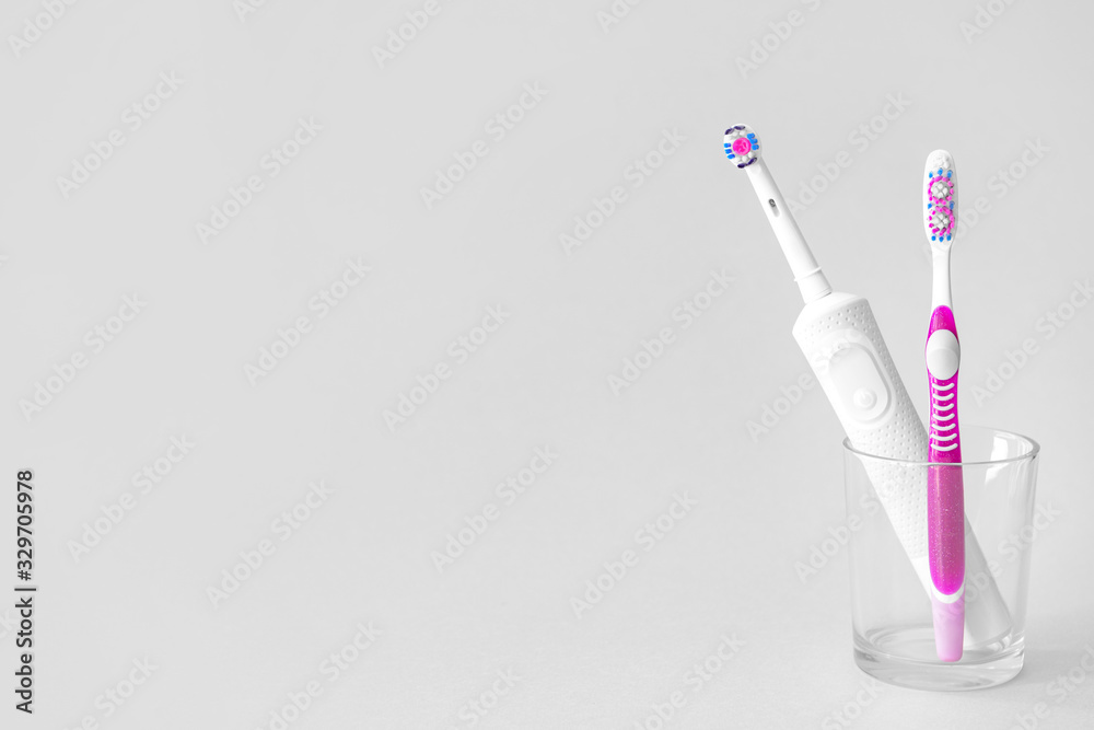 Glass with tooth brushes on light background