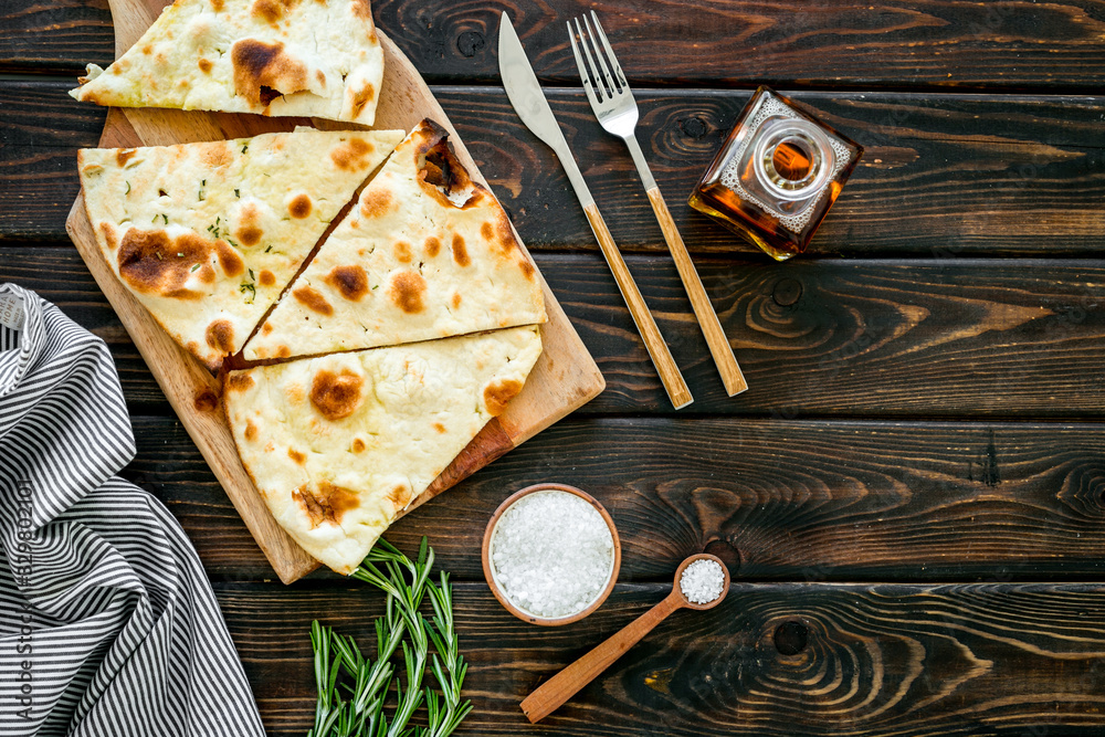 Italian focaccia with cheese and rosemary on dark wooden background top-down copy space