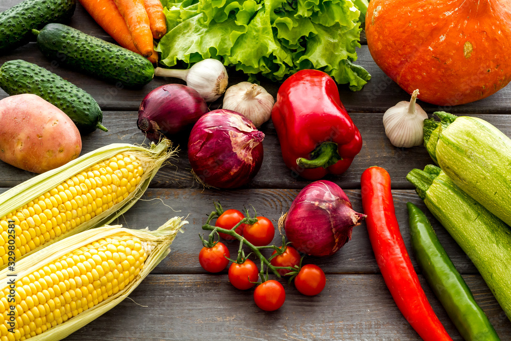 Fresh vegetables still life. Potato, cucumber, beet carrot, greenery on dark wooden background