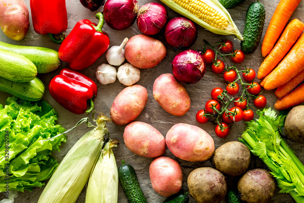 Fresh vegetables still life. Potato, cucumber, beet carrot, greenery on stone background top-down