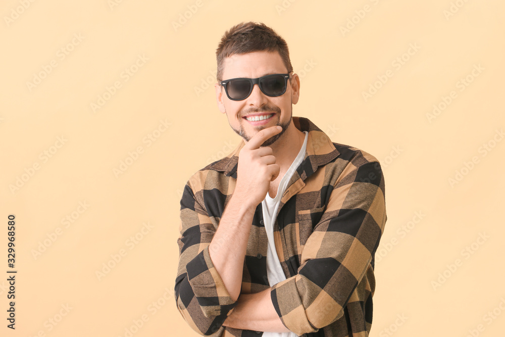 Handsome man with sunglasses on color background