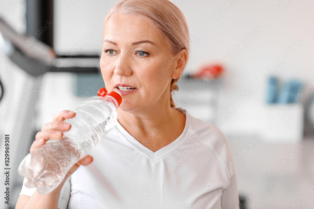 Sporty mature woman with bottle of water in gym