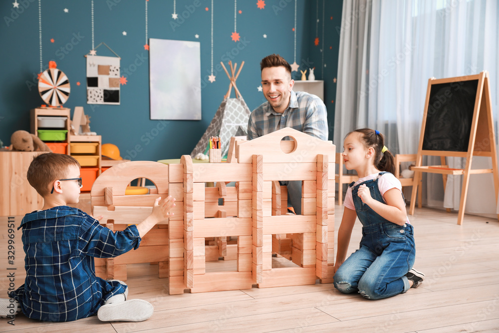 Father and little children playing with take-apart house at home