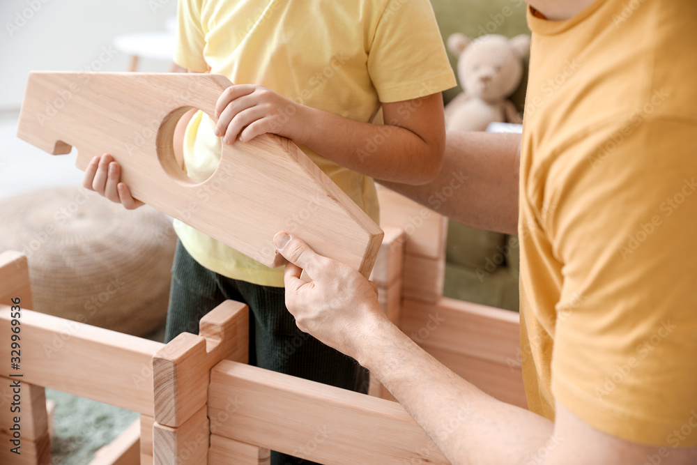 Father and little daughter playing with take-apart house at home