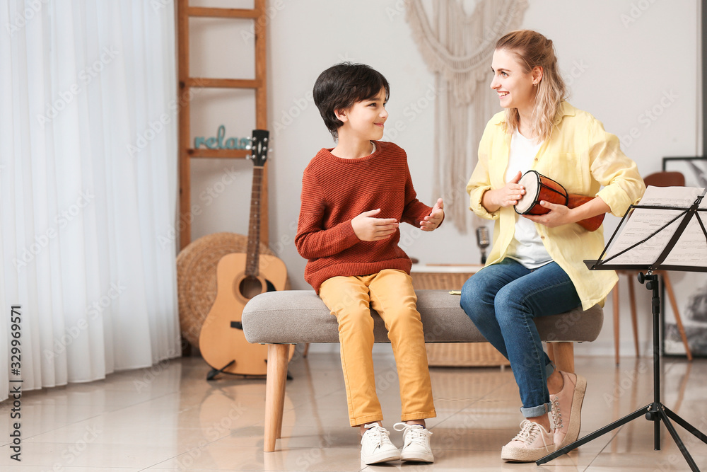 Private music teacher giving lessons to little boy at home