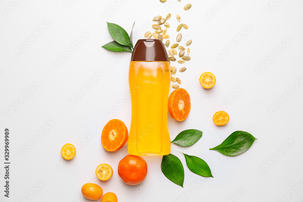 Bottle of shampoo and citrus fruits on white background