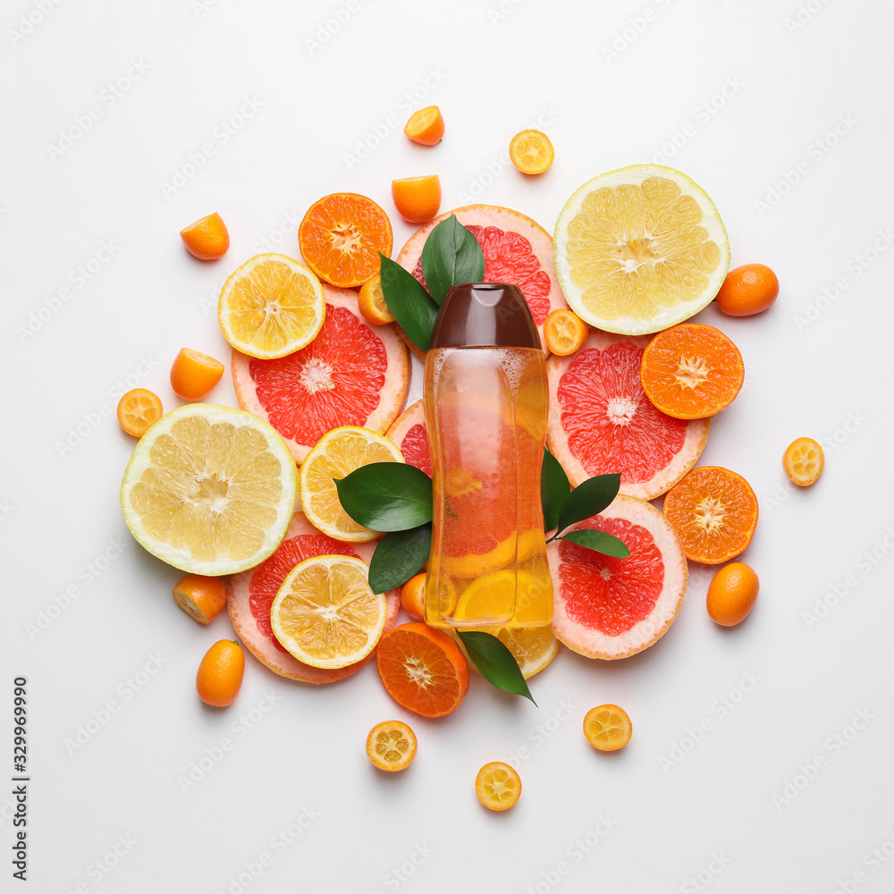 Bottle of shampoo and citrus fruits on white background