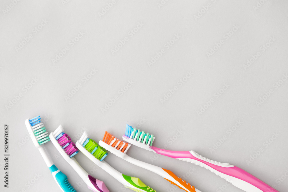 Many tooth brushes on light background