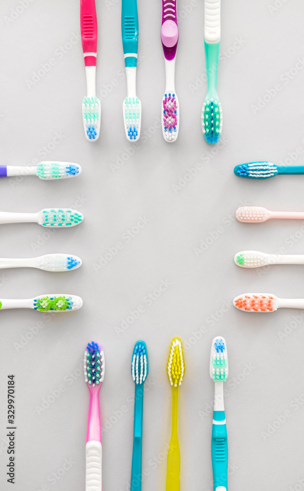 Many tooth brushes on light background