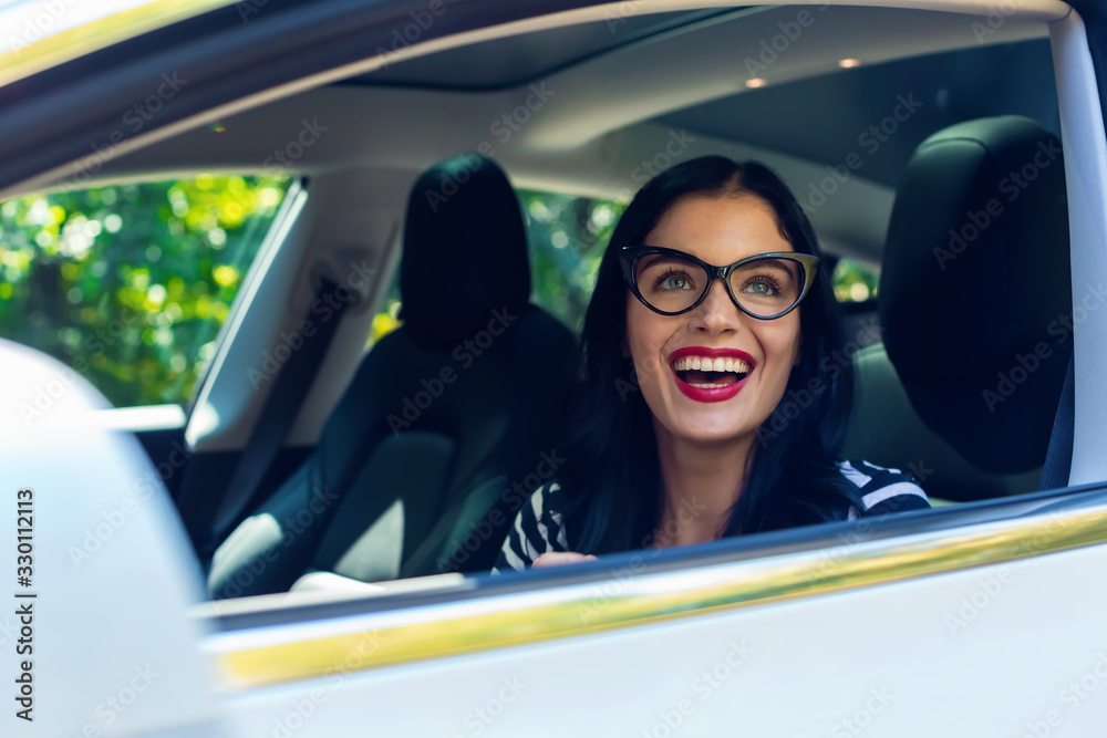 Woman in a self-driving autonomous electric vehicle with hands off the steering wheel