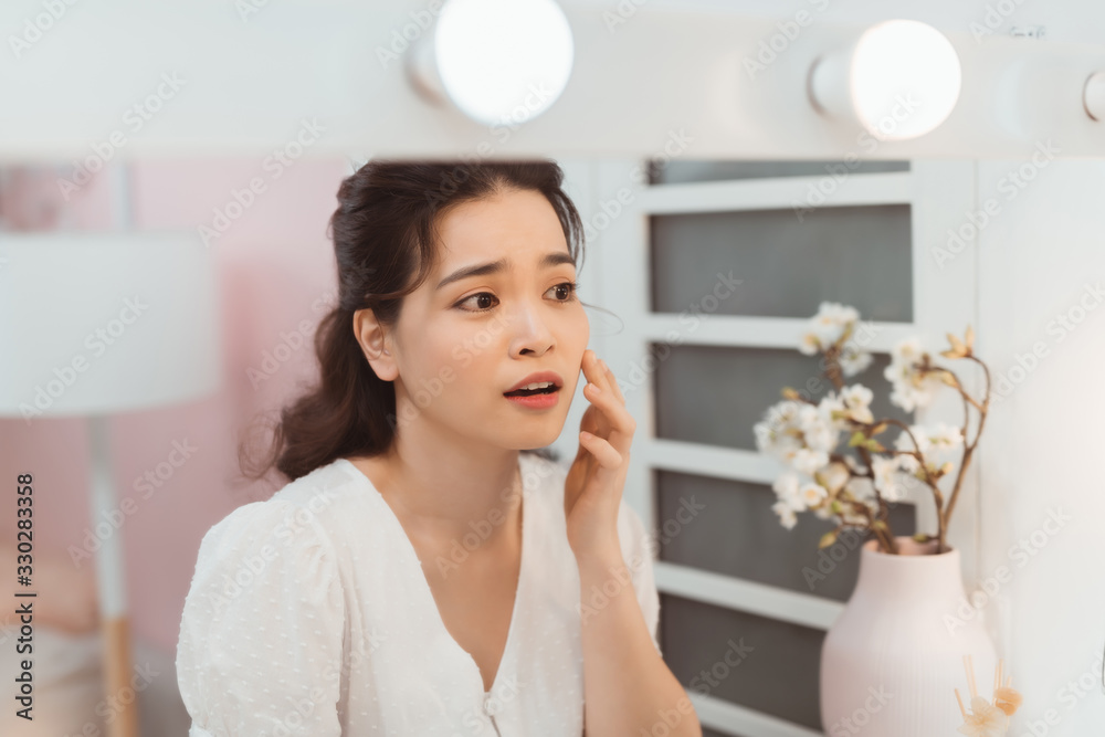 女人看起来很痛苦，因为痤疮而摸脸