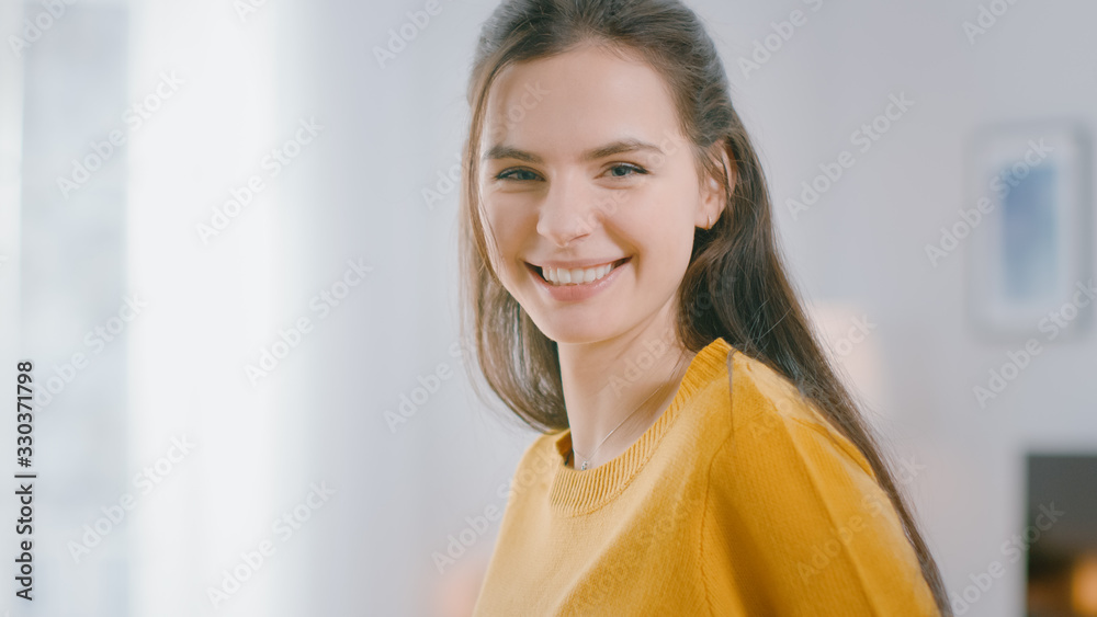 Beautiful Young Caucasian Girl with Long Dark Hair is Posing at Home. Shes Happy and Smiling. She W