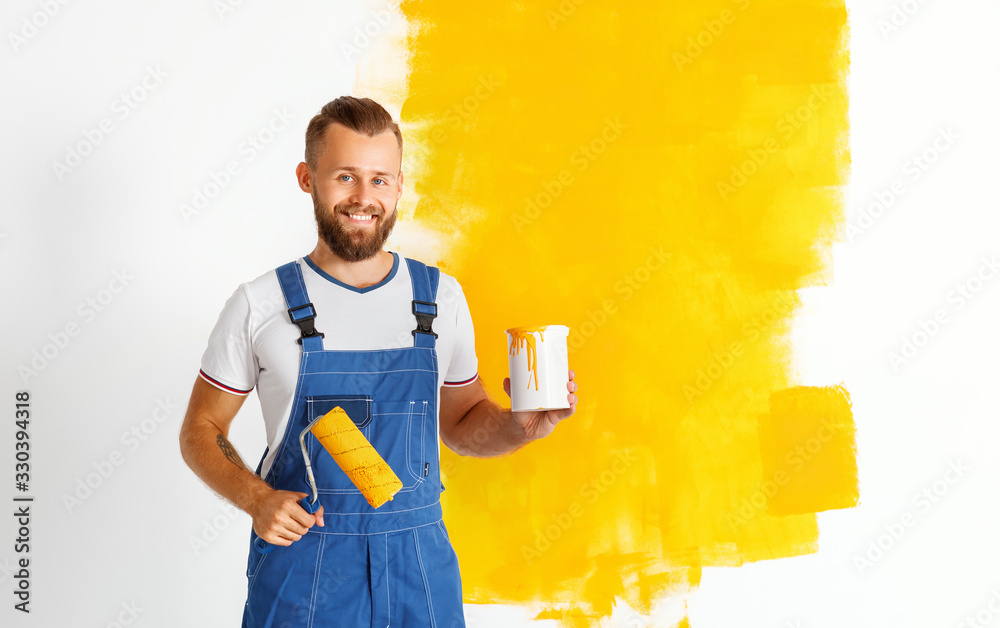 Happy man worker paints wall in   apartment.