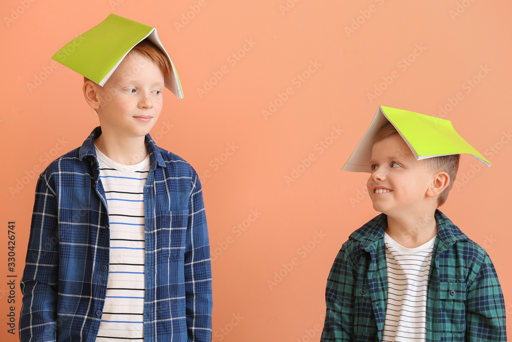 Cute little boys with notebooks on color background