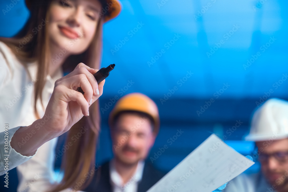 Female engineer drawing something on transparent board in office, closeup