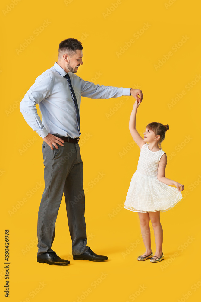 Father and his little daughter dancing against color background