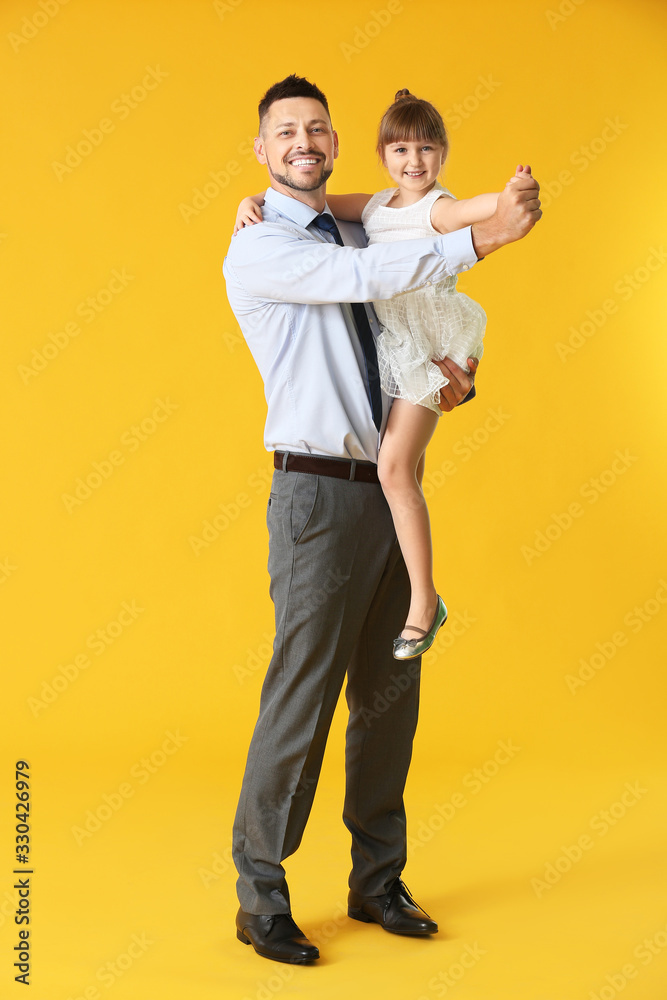 Father and his little daughter dancing against color background