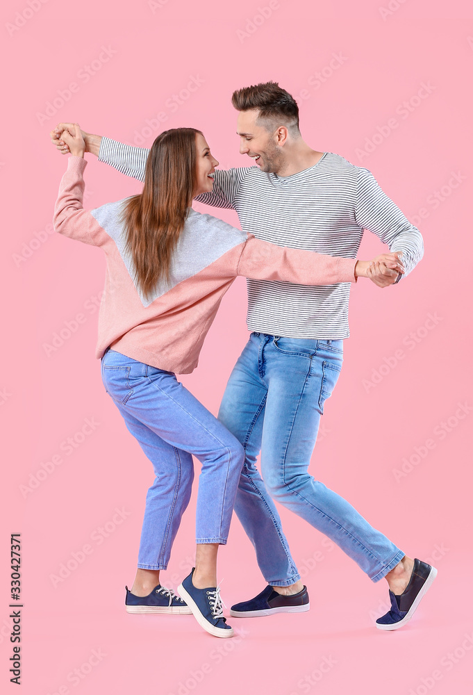 Happy couple dancing against color background