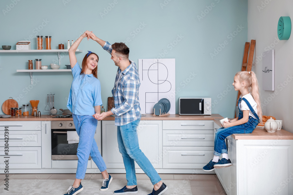 Little girl looking at her parents dancing in kitchen