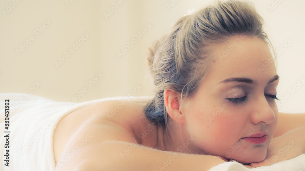 Relaxed young woman lying on spa bed prepared for facial treatment and massage in luxury spa resort.