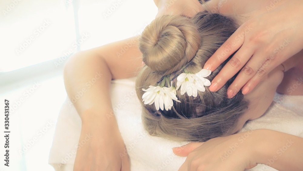 Relaxed woman lying on spa bed for neck and head massage spa treatment by massage therapist in a lux