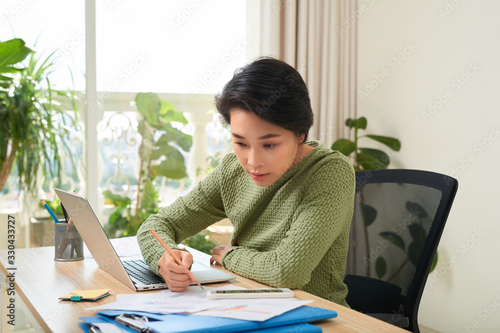 专心的女人坐在桌子旁阅读文件并做笔记