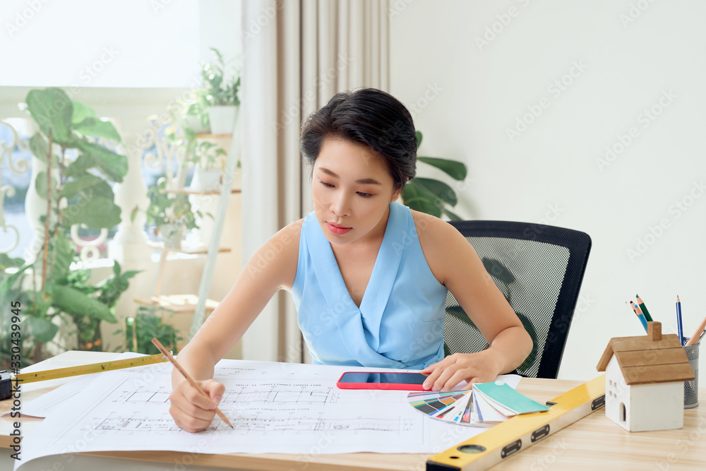 Asian female architect studying plans in office