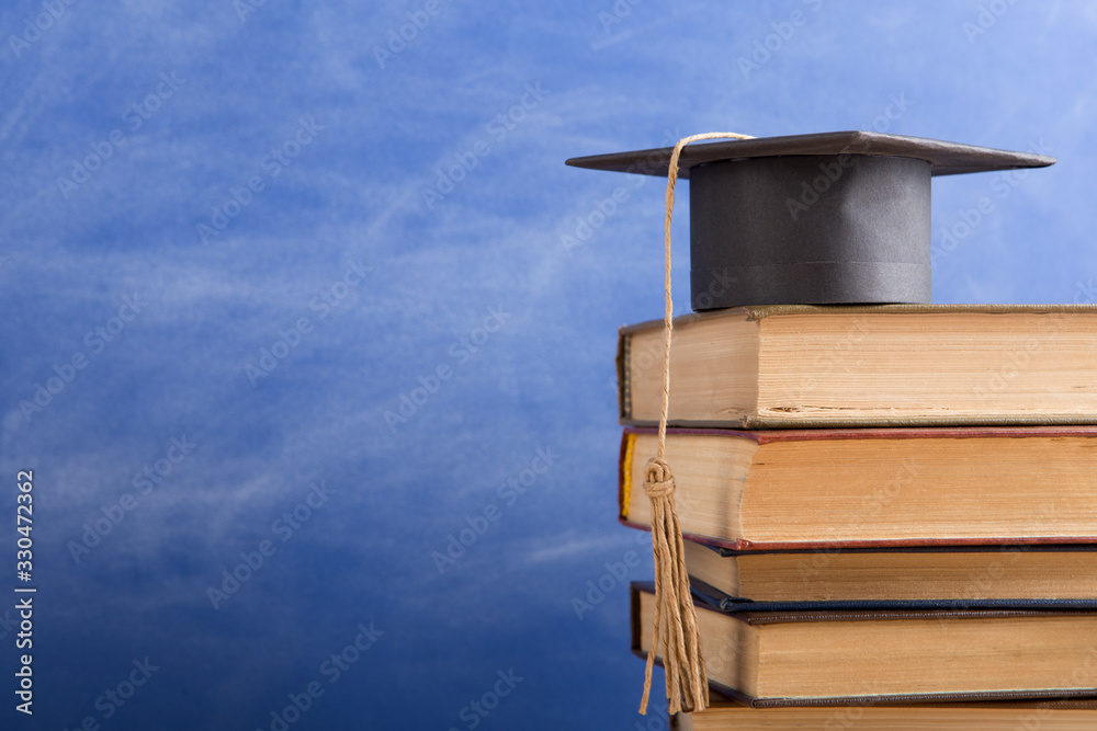 Graduation cap with books on the chalkboard background in the auditorium