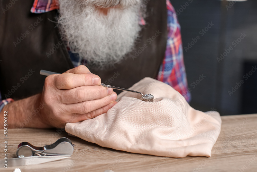 Jeweller examining adornment in workshop, closeup