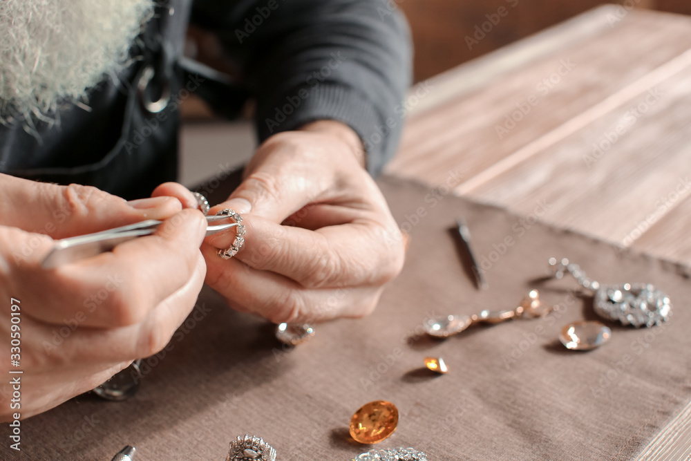 Jeweller examining adornment in workshop, closeup