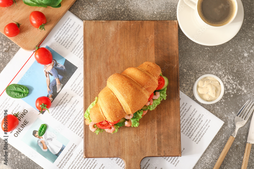 Tasty croissant sandwich with coffee and newspaper on table