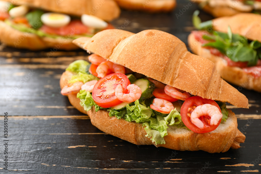 Tasty croissant sandwich on wooden table