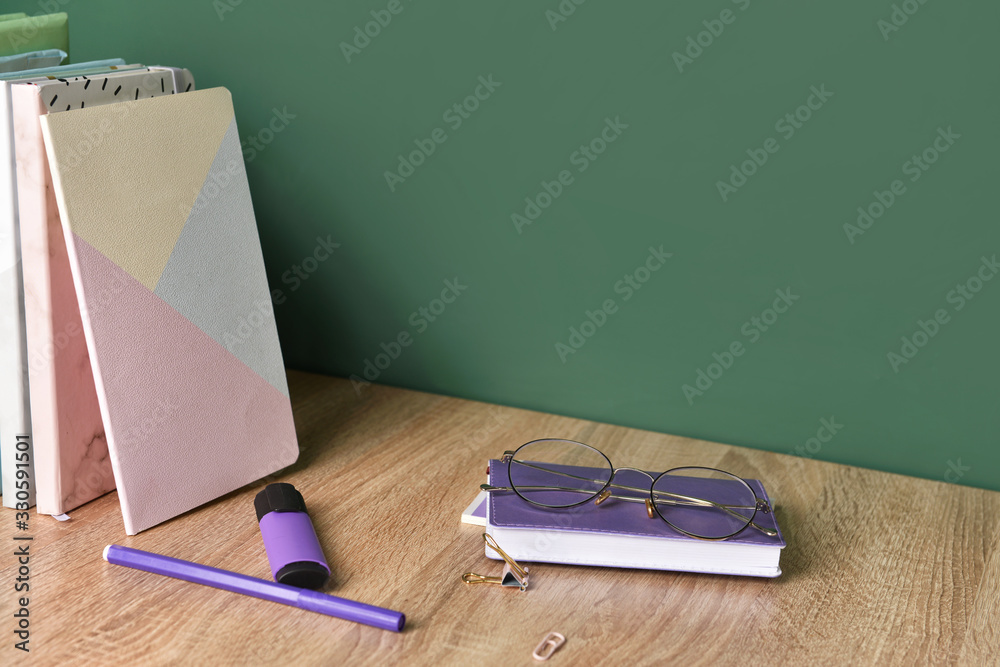 Set of school supplies on table near blackboard