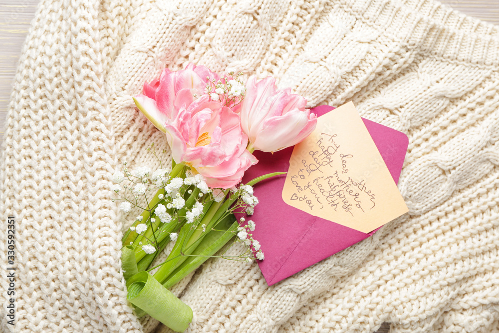 Envelope with greeting card for mother and flowers on knitted sweater