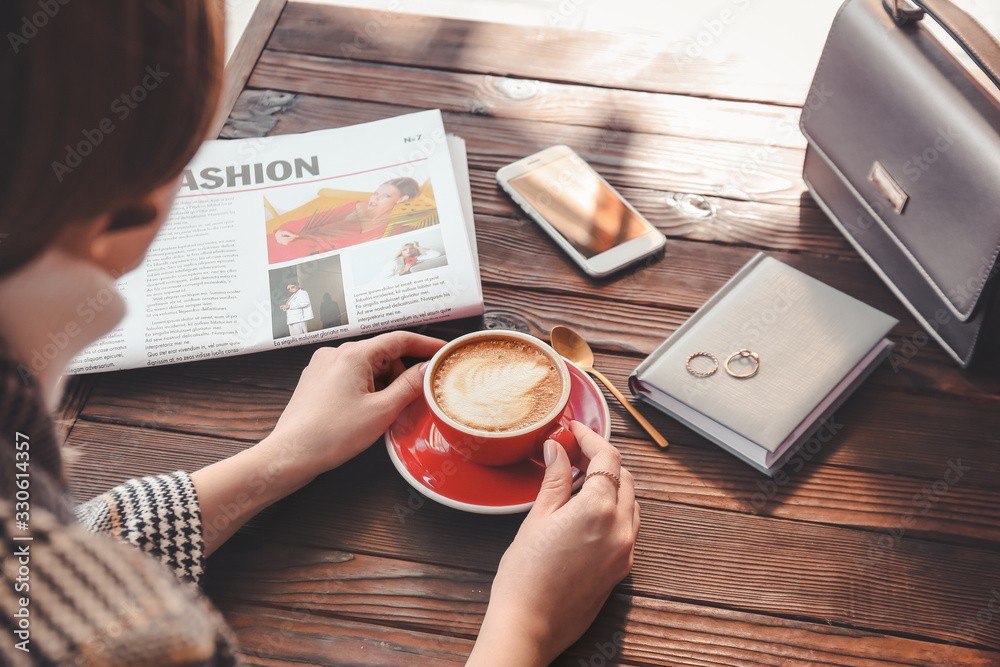 Woman drinking tasty cappuccino at wooden table