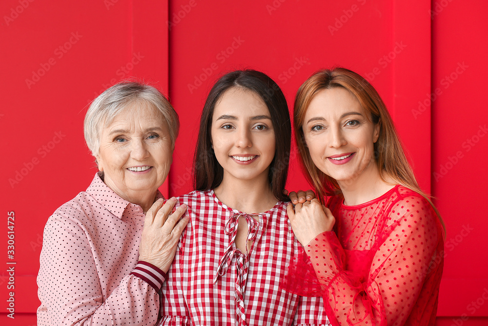 Portrait of mature woman with her adult daughter and mother on color background