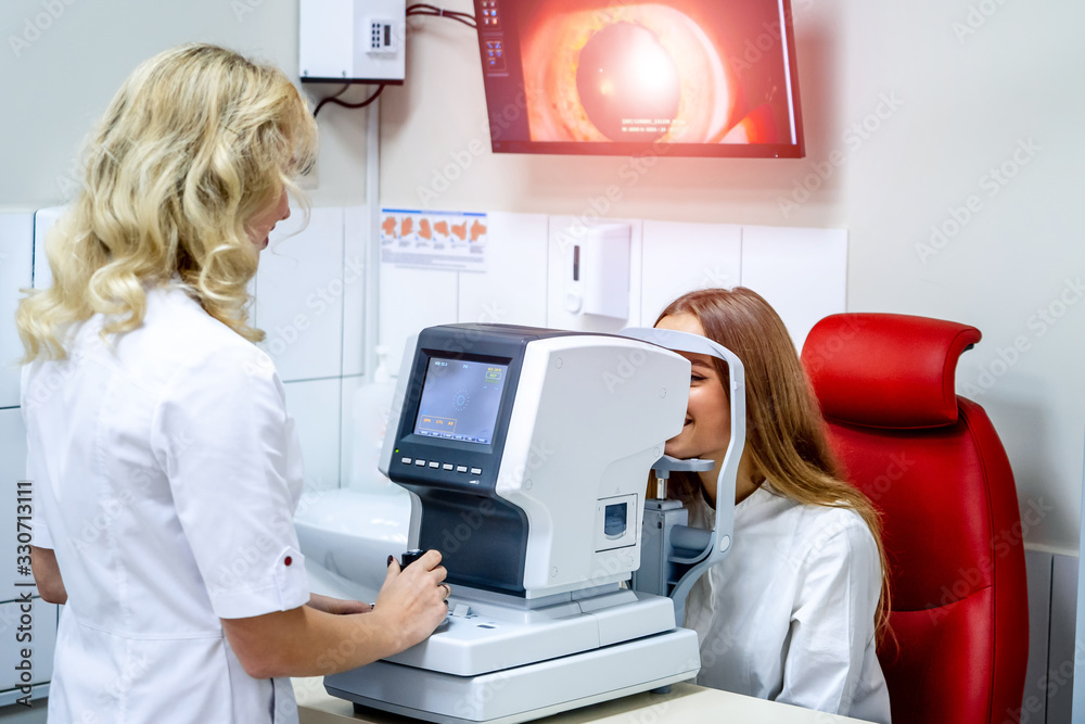 Young woman checking vision. Medical examination at the ophthalmological office. Eye health concept.