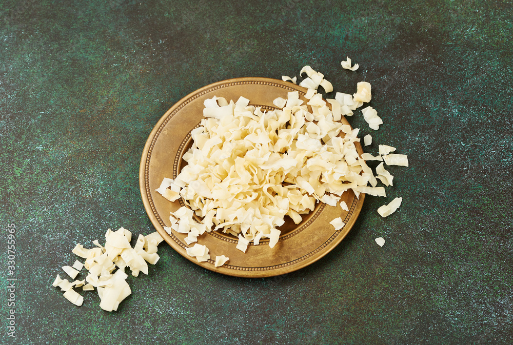 Organic Roasted coconut chips in a arabic plate on a green background.