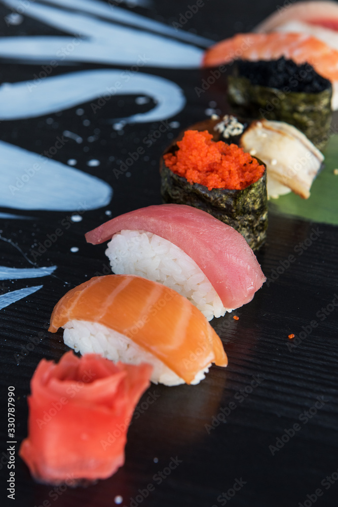 Various kinds of sushi served on wood black table.