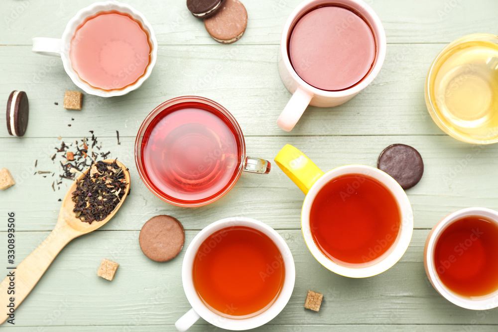 Cups with different types of hot tea on wooden background