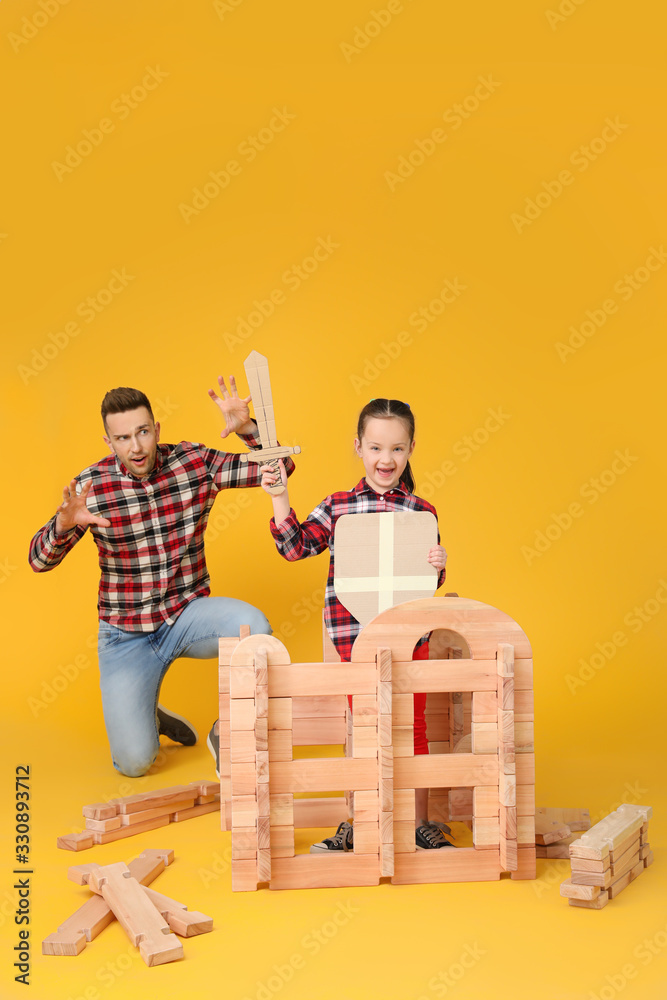 Father and little daughter playing with take-apart house on color background