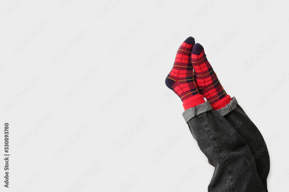 Legs of little child in socks and jeans on light background