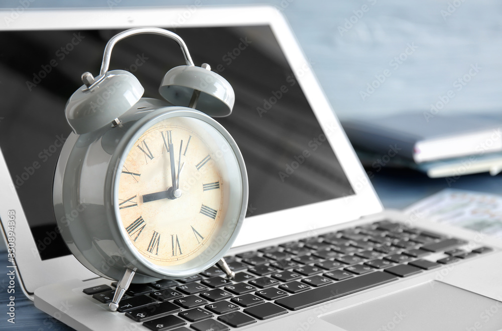 Alarm clock with laptop on table, closeup. Time management concept